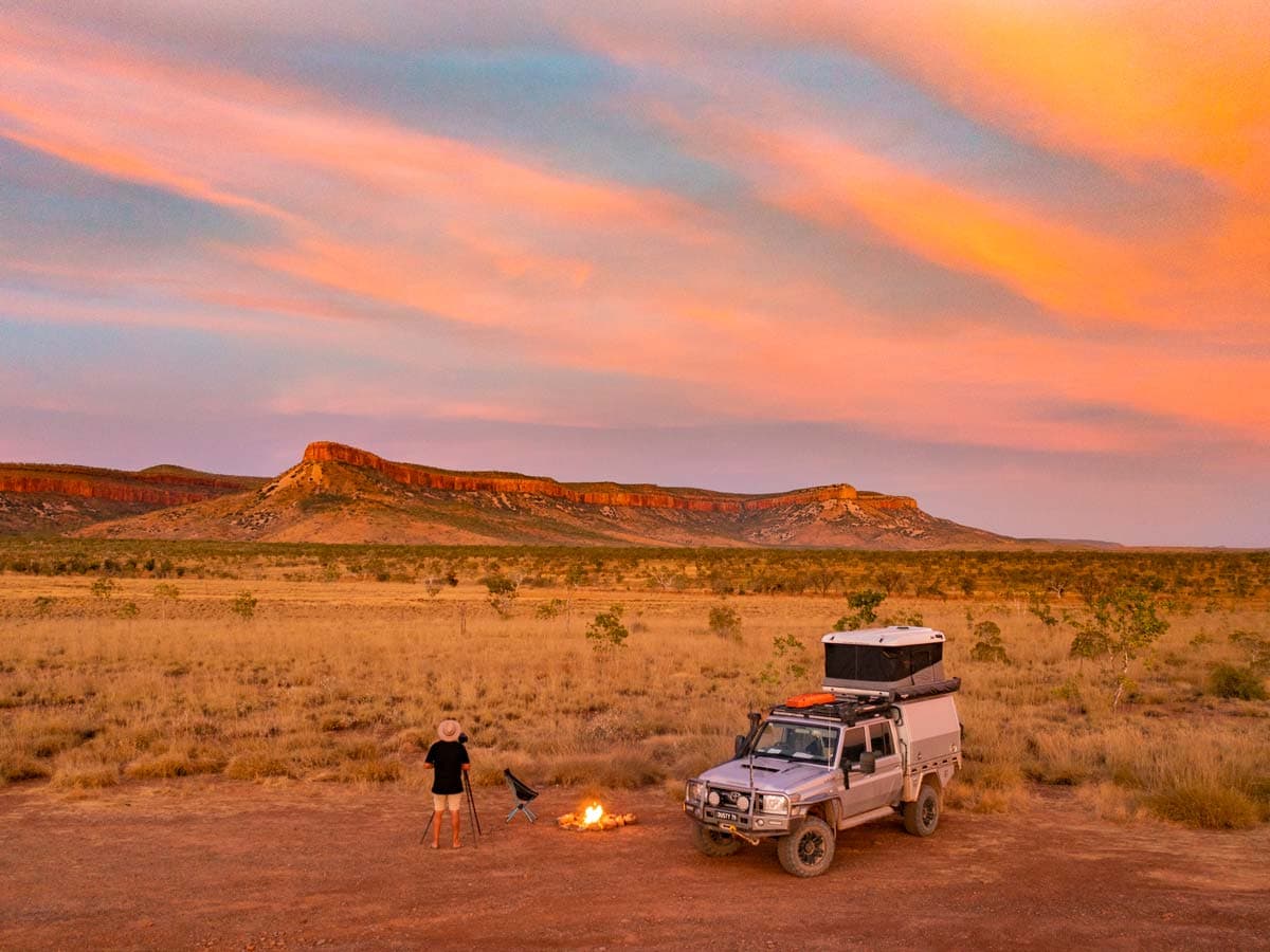 a man setting up a bonfire outside his 4WD in El Questro