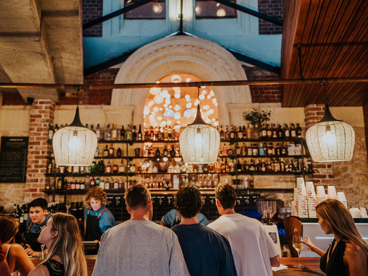 people lining up at the well-lit bar counter of Mr Chapple, Fremantle