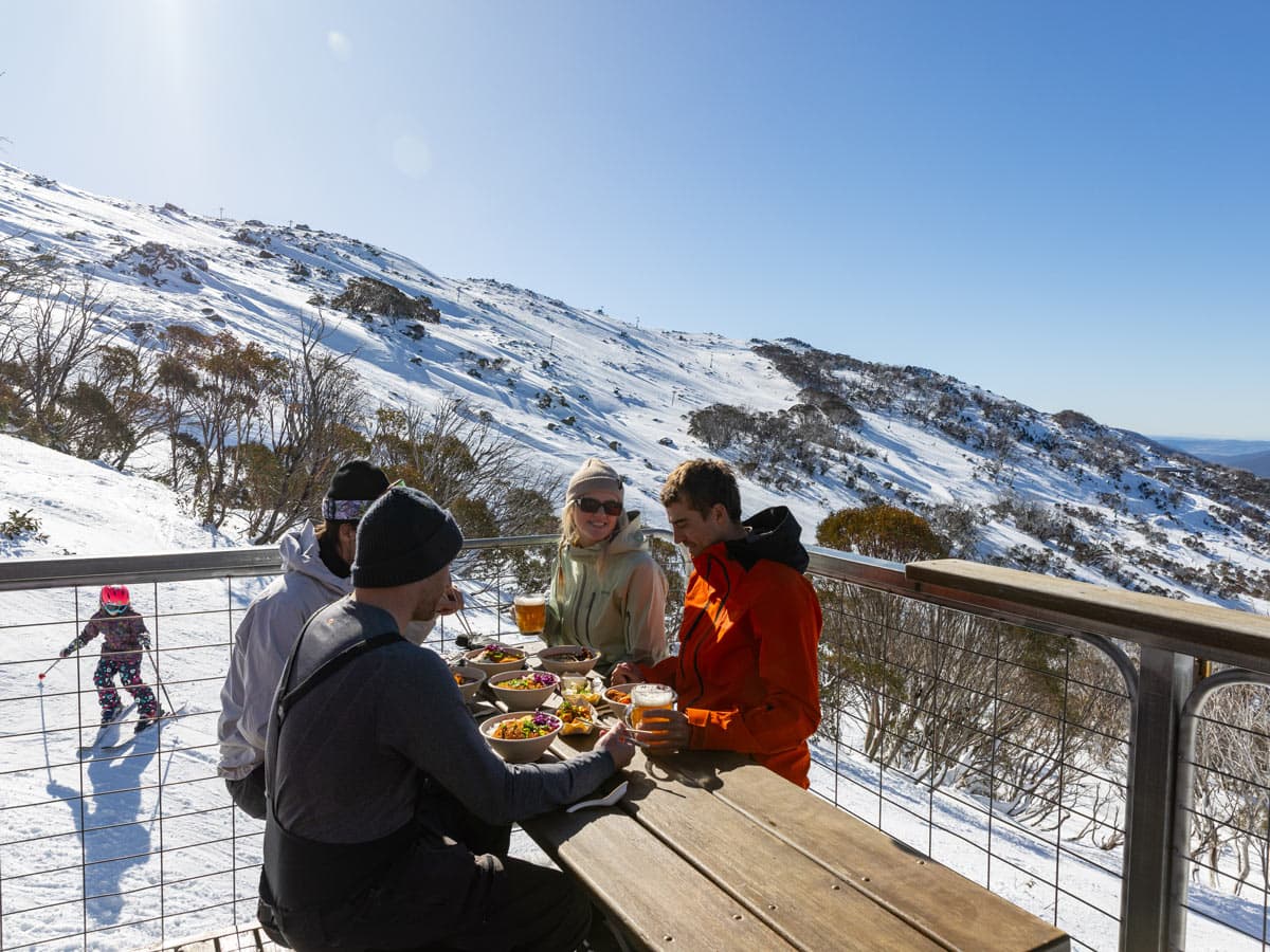 friends dining on the outdoor deck of Black Sallees, Thredbo