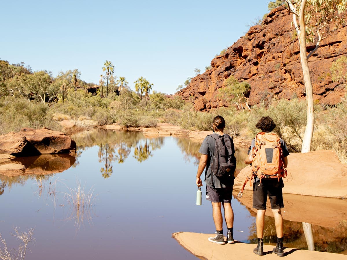 Two men hiking beside Finke River in Finke Gorge National Park