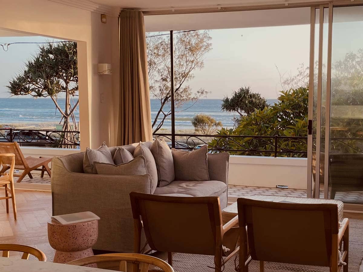 a living room with curtains opening up to scenic sea views