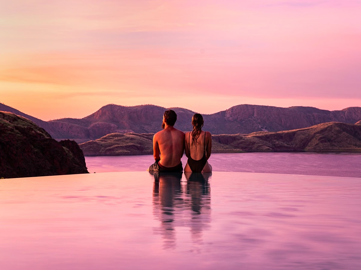 a couple sitting by the edge of the infinity pool during sunset at Lake Argyle Resort, WA